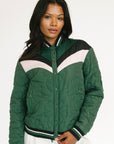 Woman wearing a green quilted jacket with white and black accents on a white background