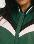Close-up of a person wearing a green, black, and pink jacket.