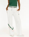 Person wearing a green top and white pants with green accents on a white background