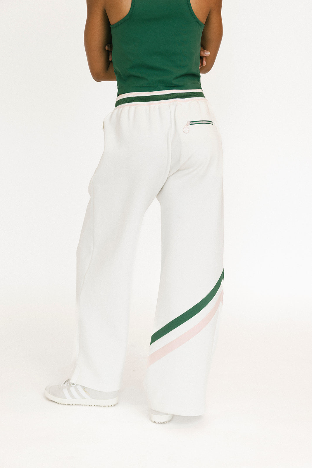 Person wearing white pants with green stripes and a green top on a white background