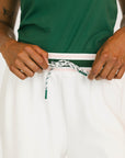 Person wearing a green sleeveless top and white pants with a green stripe.