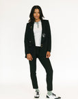 Person wearing a black blazer and pants with a white shirt on a white background