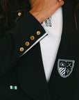 Black blazer with gold buttons and a white shirt, featuring a logo on the chest.