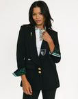 Woman wearing a black blazer with green and white accents on a white background