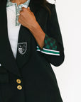 Person wearing a black blazer with green and white accents on a white background