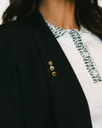 Black blazer with gold buttons worn by a person, with a blurred background
