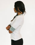 Woman wearing a white blouse with patterned cuffs on a white background
