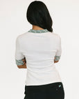 Woman wearing a white blouse with patterned cuffs and collar on a white background