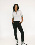 Woman wearing a white polo shirt with black pants on a white background