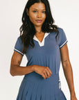 Woman wearing a blue polo with white accents on a plain background