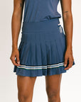 Person wearing a blue pleated skirt with white stripes on a plain background
