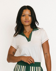 Woman wearing a white blouse with green trim and green striped pants against a white background