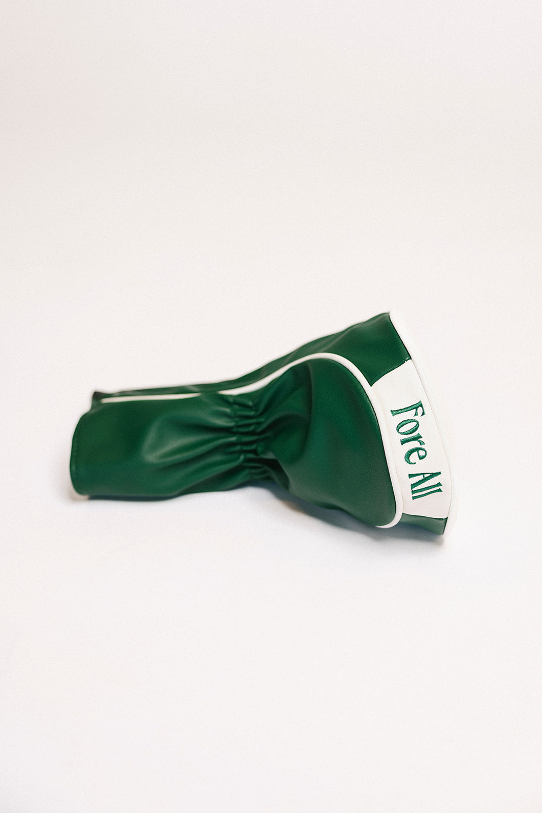 Green golf club head cover with 'Fore All' text on a white background