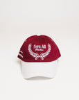 A person wearing a burgundy and white baseball cap with text and leaf patterns.