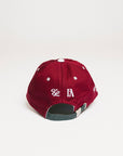 A person wearing a burgundy and white baseball cap with text and leaf patterns.