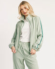 Woman wearing a light green tracksuit with a white top on a white background