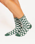 Green and white checkered socks worn by a person on a white background
