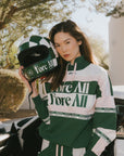 A woman wearing a green and pink racing shirt with colorblocking and text embroidery on it.