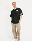 Man wearing a black and beige polo shirt with '04' on a white background