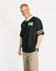 Man wearing a black and beige polo shirt with '04' on a white background