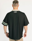 Man wearing a black sports jersey with 'FORE' branding on the back, standing against a white background.