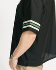 Man wearing a black and beige polo shirt with '04' on a white background