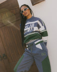 A woman wearing an indigo and green long-sleeved racing shirt with colorblocking and text embroidery.