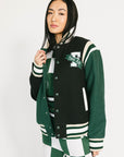 Person wearing a green and black varsity jacket with a logo on a white background