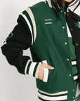 Green and black varsity jacket with white accents on a plain background