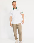 Man wearing a white polo shirt with green collar and beige pants on a white background