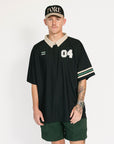 Person wearing a black sports jersey with white lettering and green shorts on a white background
