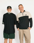 Two men wearing matching black and beige outfits with 'FORE' branding on a white background.