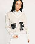 Woman wearing a cream sweater with black lettering and white skirt on a white background