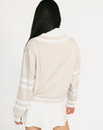 Person wearing a beige sweater with white stripes on a plain background