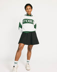 Woman wearing a green and white sweater with 'FORE' text on a plain background