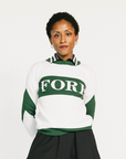 Woman wearing a green and white sweater with 'FORE' text on a plain background