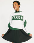 Woman wearing a green and white sweater with 'FORE' text on a plain background