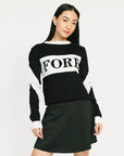 Woman wearing a black and white sweater with 'FORE' text, black skirt, and black boots on a white background