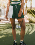 Person wearing a green and white striped top with a green skirt and black Adidas shoes in an outdoor setting.