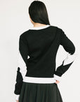 Person wearing a black and white sweater with 'FORE' printed on it against a plain background