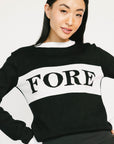 Person wearing a black and white sweater with 'FORE' printed on it against a plain background