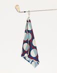 Patterned golf towel hanging on a golf club against a white background