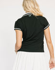 Person wearing a black polo shirt with a small flag emblem on the neck against a white background