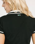 Black polo shirt with white trim worn by a person, on a plain background