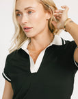 Woman wearing a black and white polo shirt against a plain background