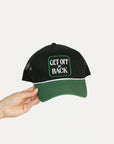 Black and green cap with 'GET OFF MY BACK' text held by a hand on a white background.