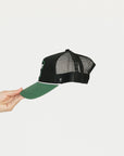 Black and green cap with 'GET OFF MY BACK' text held by a hand on a white background.
