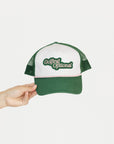 Green and white cap with 'Golfing Optional' text held by a hand on a white background.