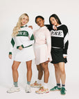 Three women wearing sweaters with 'FORE' text on a white background