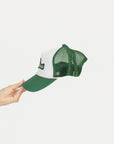 Green and white cap held by a hand on a white background